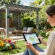 Homeowner using a 3D pergola configurator in a vibrant garden for design inspiration.