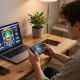 Player engaging with dn88 casino app on smartphone in cozy home office setting, showcasing online gaming excitement.