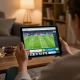 Socolive link displayed on tablet as user enjoys a live soccer match at home with snacks